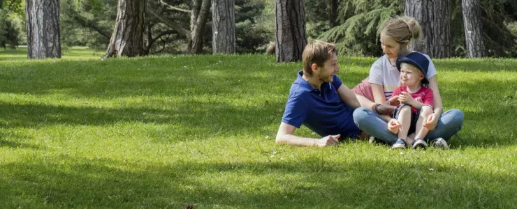 A family sit on the grass at Kew Gardens