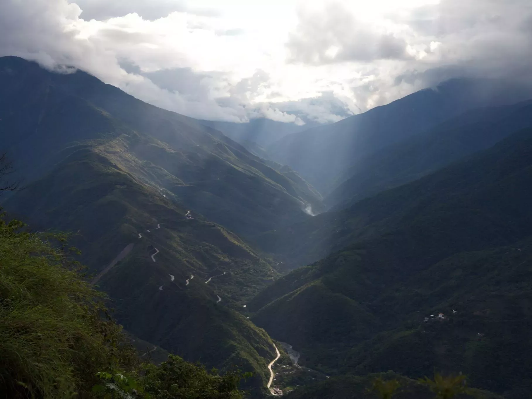 Sunlight bursts through cloud onto a green valley