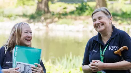 A pair of people smiling and standing in front of a pond