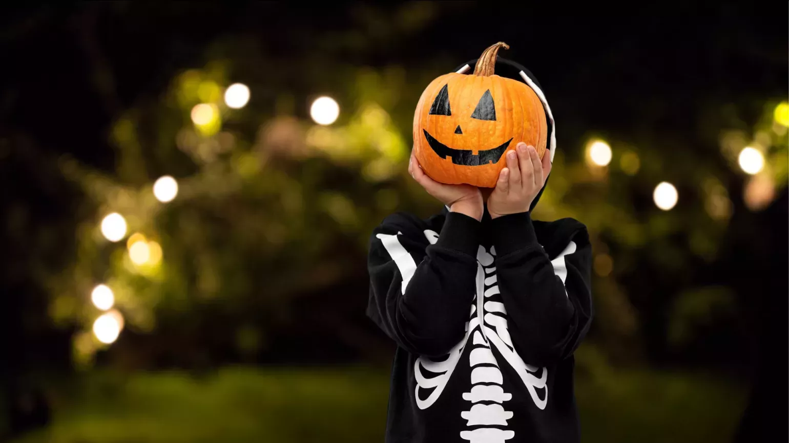 Person dressed in skeleton costume with jack-o-lantern for a head