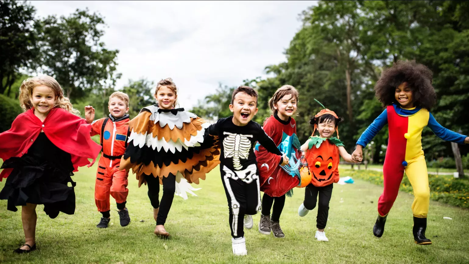 A group of kids in Halloween costumes running through Kew Gardens