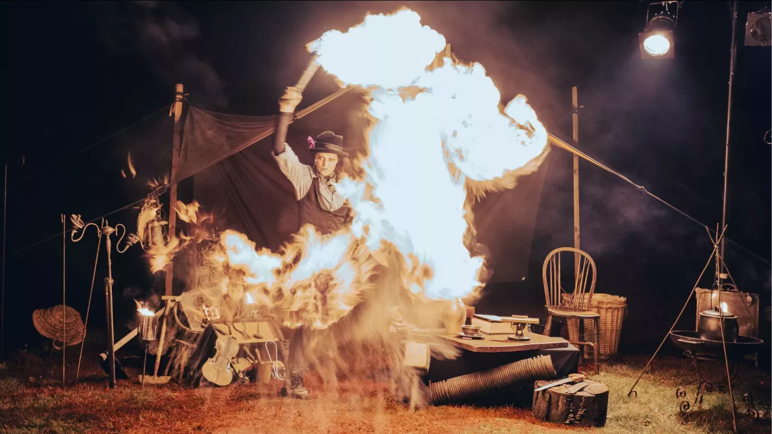 A person in front of a tent throwing fire around