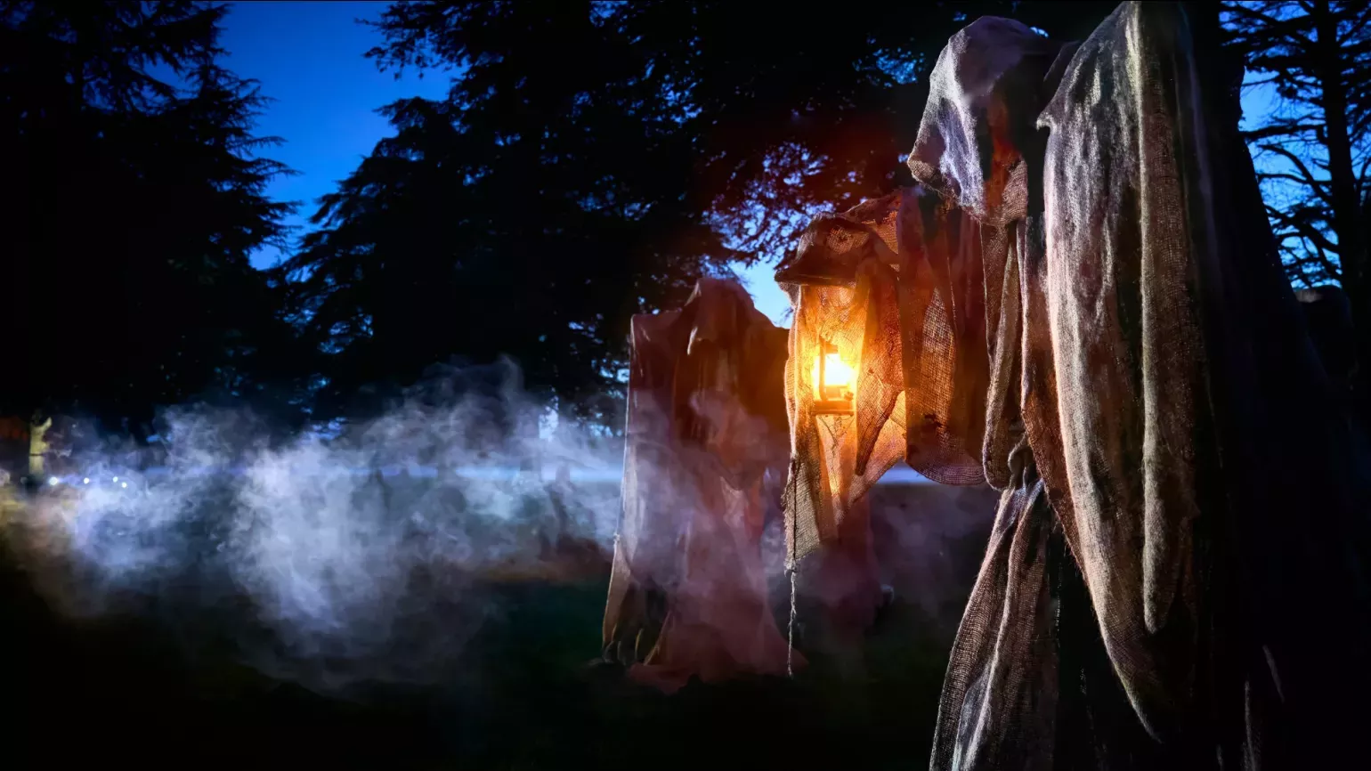 A wraith covered in cloth and holding a lantern in a misty forest