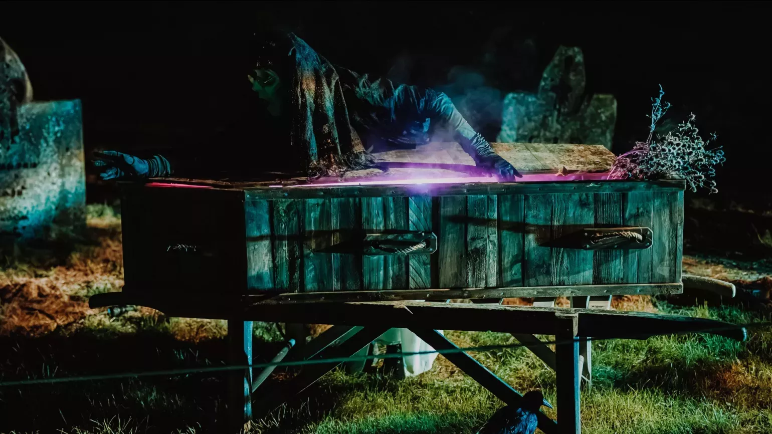 A zombie rising from a lit coffin 