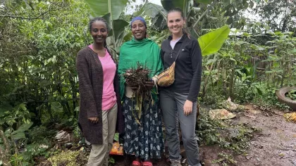 Three women stand infront of an enset plant