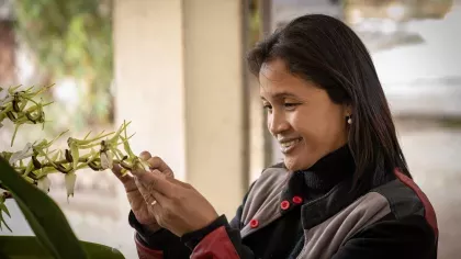 Person smiling whilst holding a delicate orchid flower