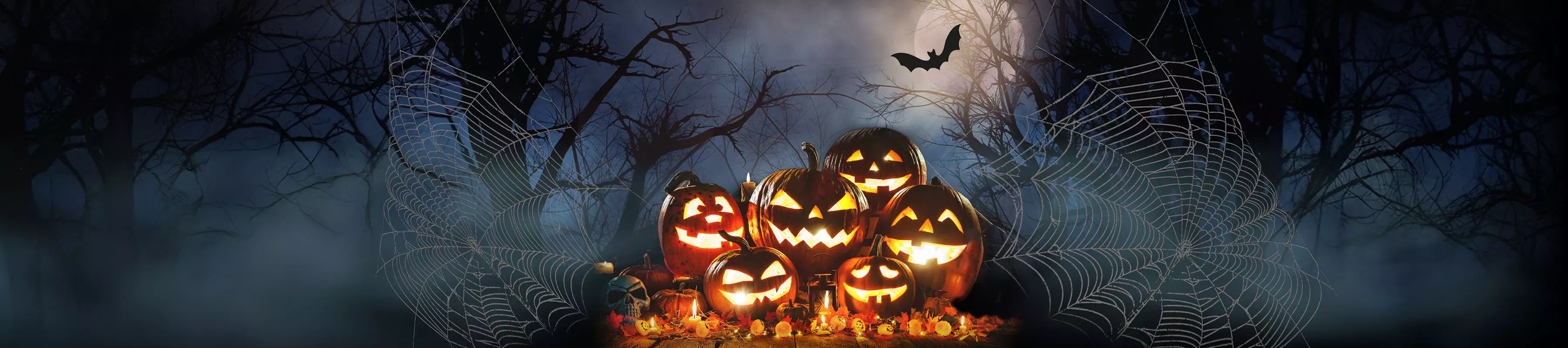 A pile of glowing jack-o-lanterns against a dark misty background with cobwebs and bats