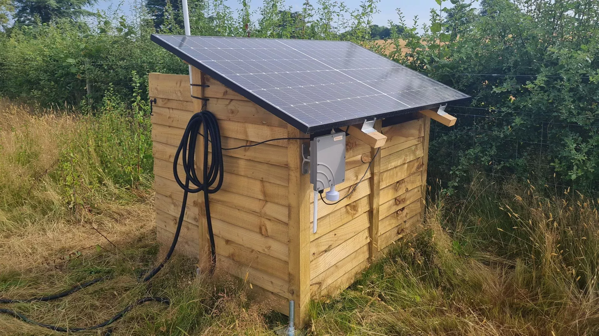 A wooden shed with a black solar panel on the roof