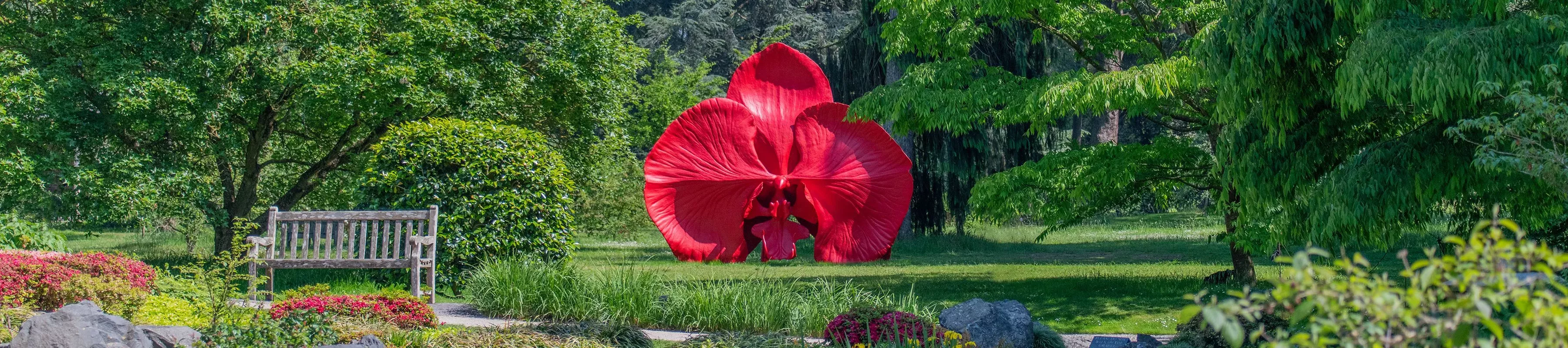 A large red orchid sculpture sitting in a green garden