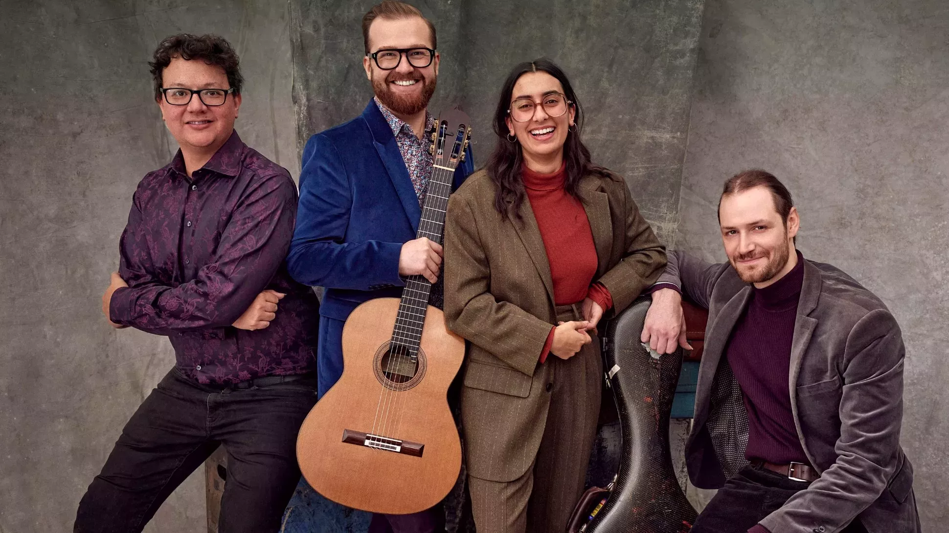 A group of four people, with one holding an acoustic guitar