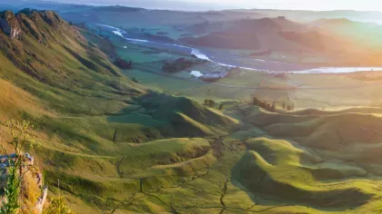 Mountain range view with sun rising in the background, illuminating the entire scenery or vegetation-covered ground.