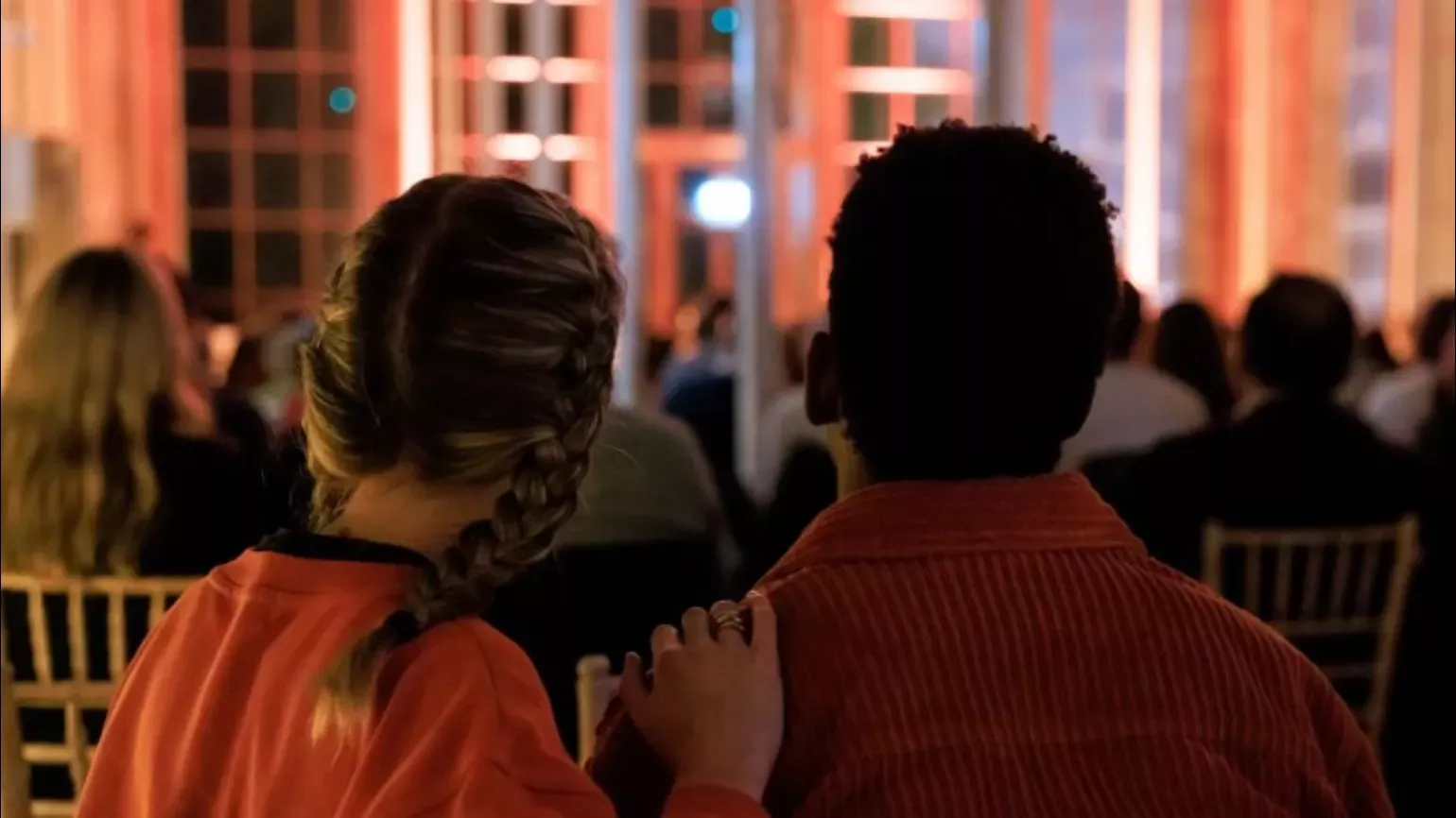 Two people watching a musical performance lit by candles