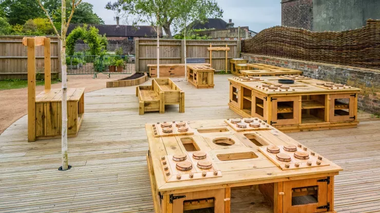 Children's outdoor play kitchen area with wooden tables and "stoves"