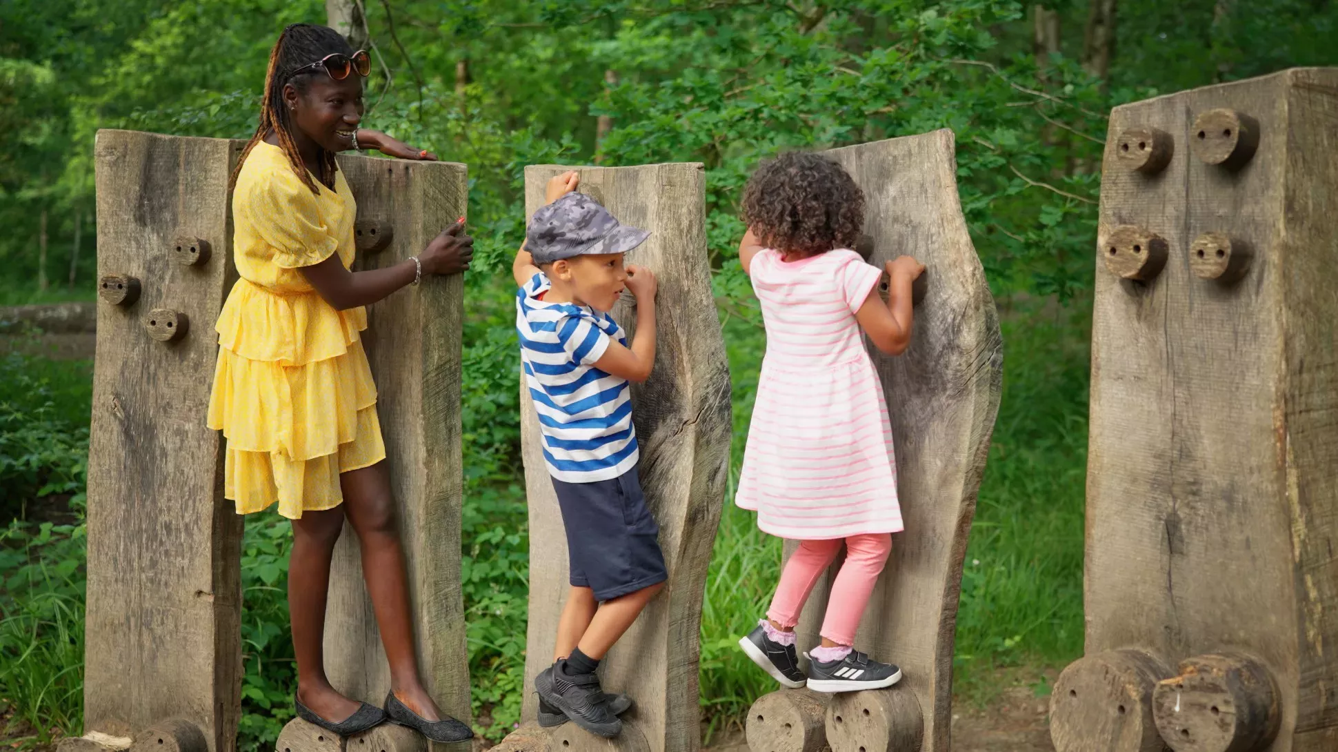 A family play on a set of logs in a forest